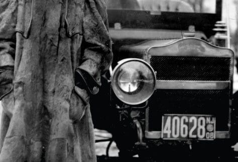 Historical photo of a woman in an early 1900s outfit standing next to a vintage car. Text reads, "She Couldn't Vote. You Can.